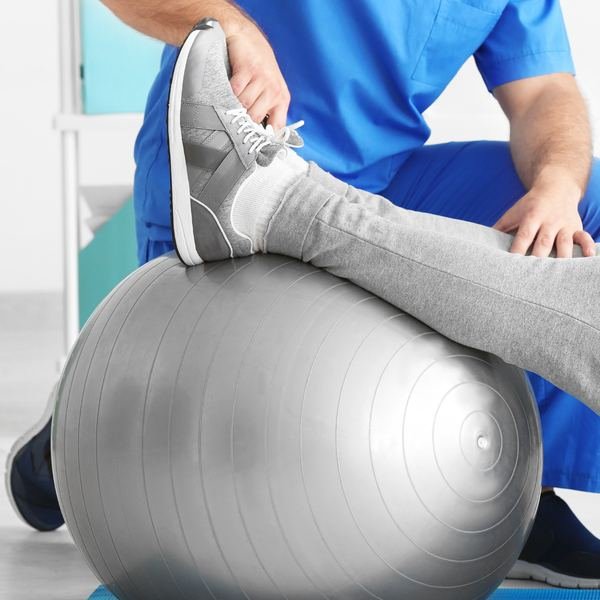 Fisioterapeuta conduzindo exercício com bola durante atendimento